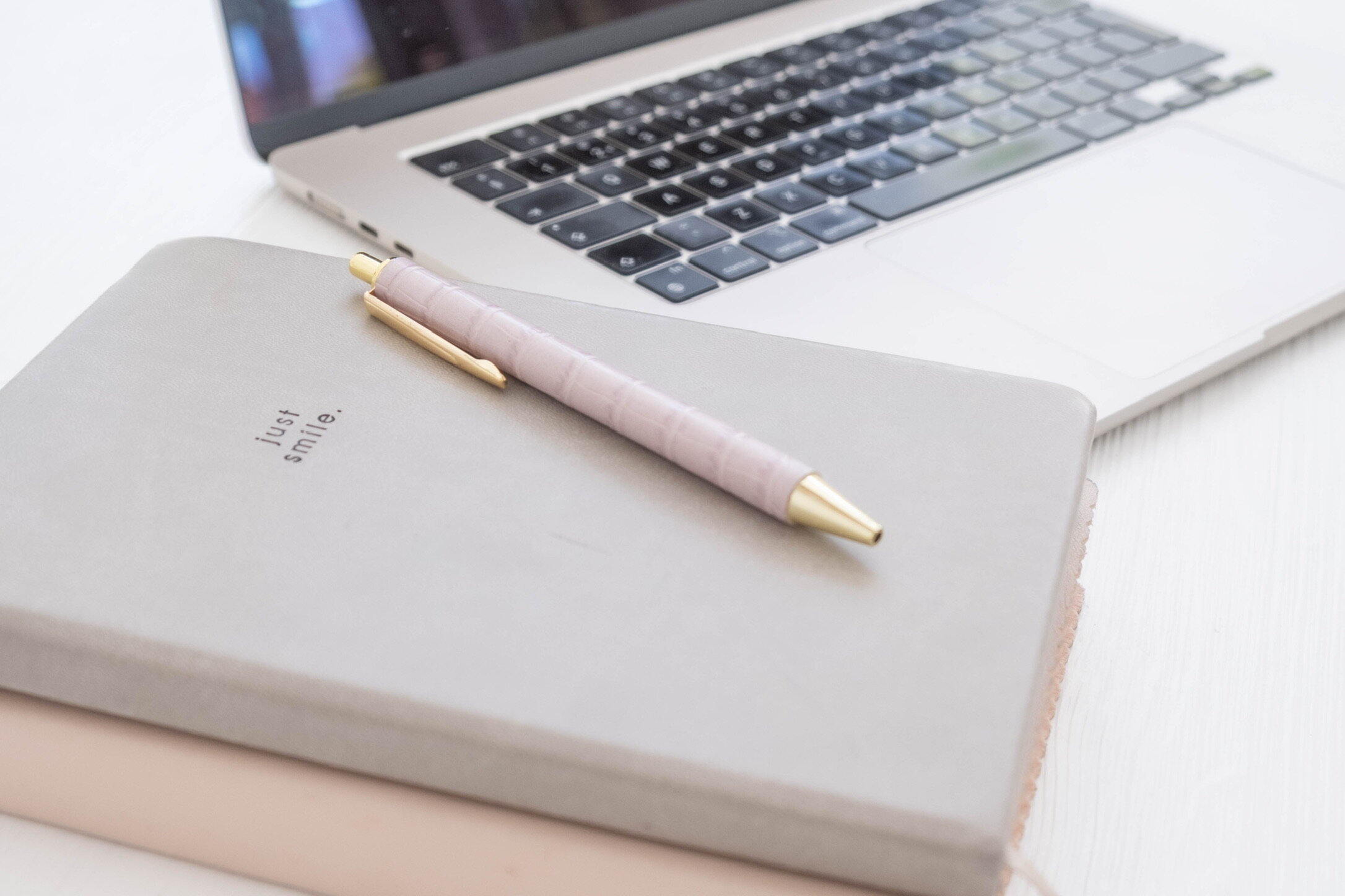 Laptop met notitieboek en pen op een licht bureau